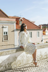 a lady in a white vest, a white jacket and a white skirt with black polka dots